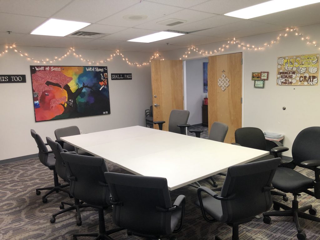 Group therapy room at Crossroads Program with chairs around table, motivational wall art, and welcoming space for addiction recovery meetings