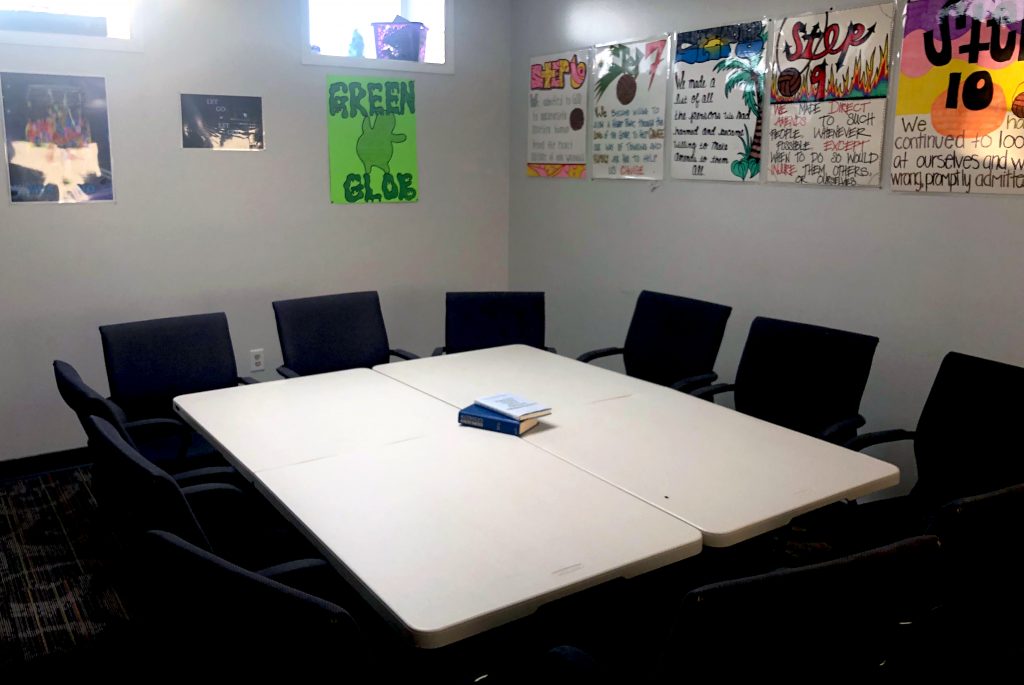 Small group meeting room at Crossroads Program with tables, chairs, and colorful 12-step recovery posters on the wall