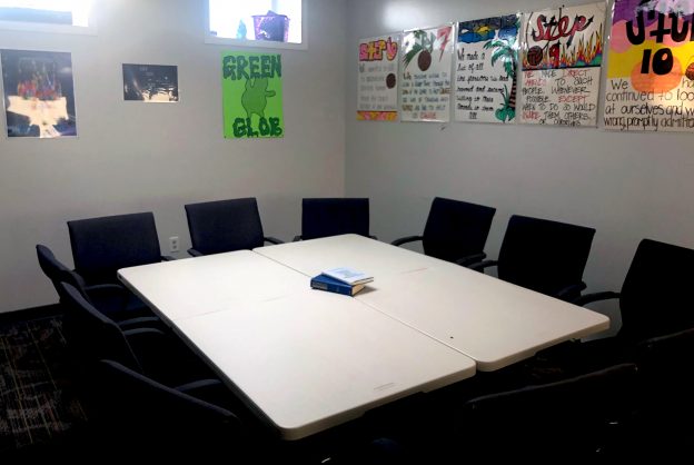 Small group meeting room at Crossroads Program with tables, chairs, and colorful 12-step recovery posters on the wall