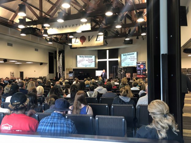 Large audience attending Crossroads Program Missouri event with speaker presenting on substance abuse awareness, prevention, and addiction recovery support
